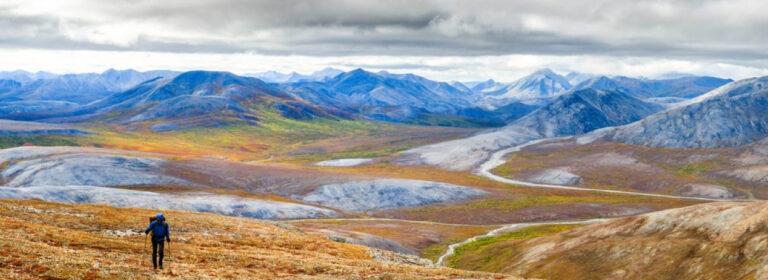 Solo hiker in mountainous landscape with cloudy sky in background